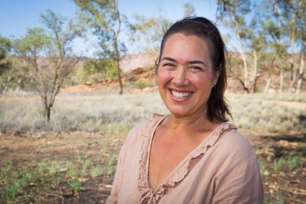 Catherine Liddle smiling in a portrait taken outdoors in arid looking bushland.