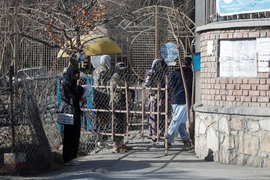 An Afghan female student stands in front of the entrance gate of Kabul University.