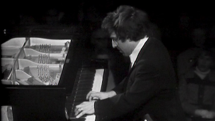 Black and white image of a man sitting at a piano