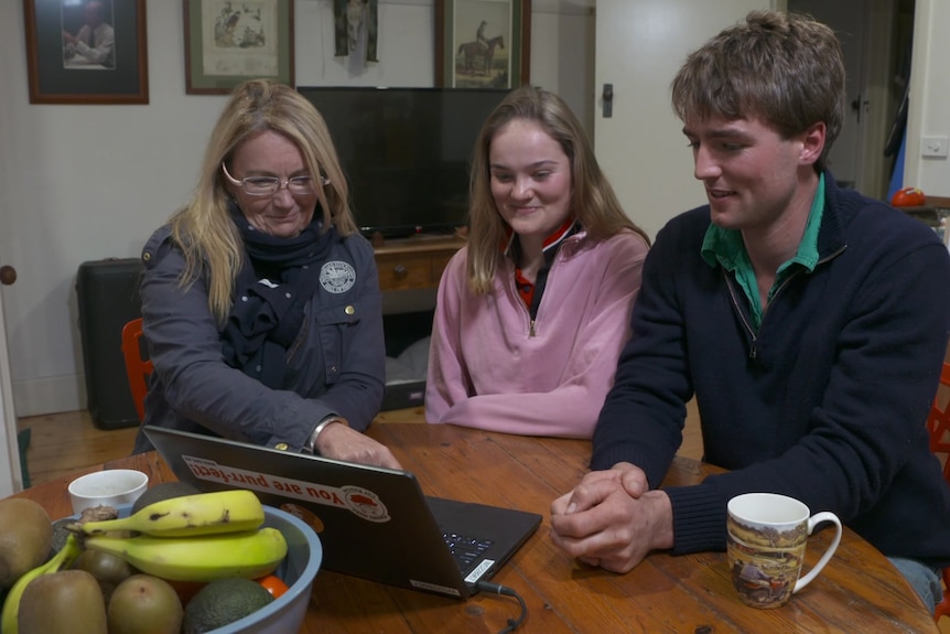 Photo of three people watching a computer screen.