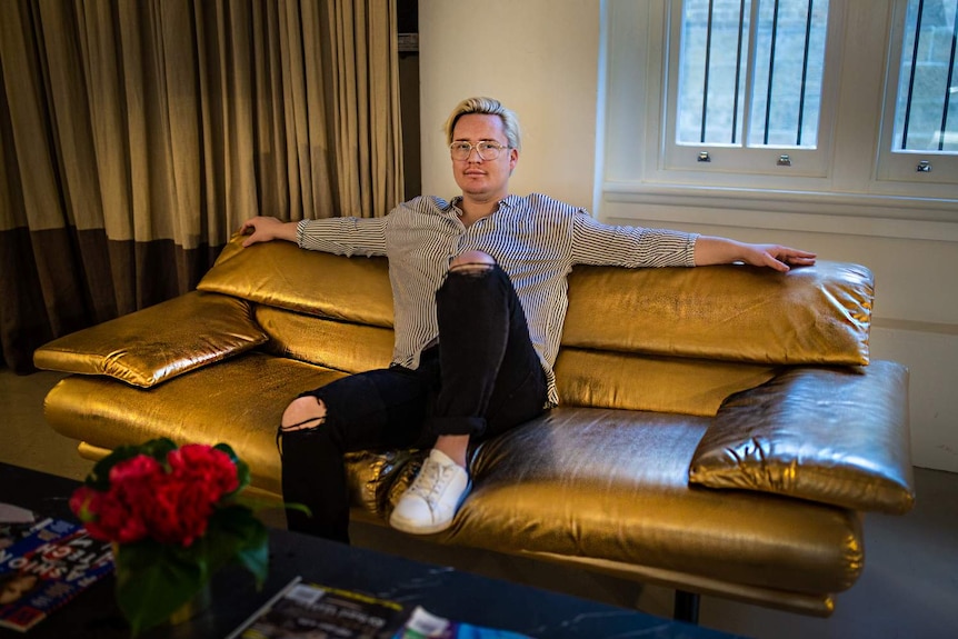 A man sitting on a couch, with his arms spread out.