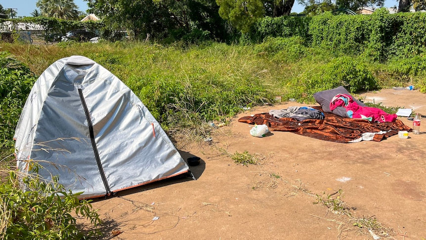 A tent next to some bedding outside on concrete.