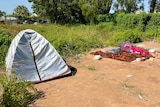 A tent next to some bedding outside on concrete.