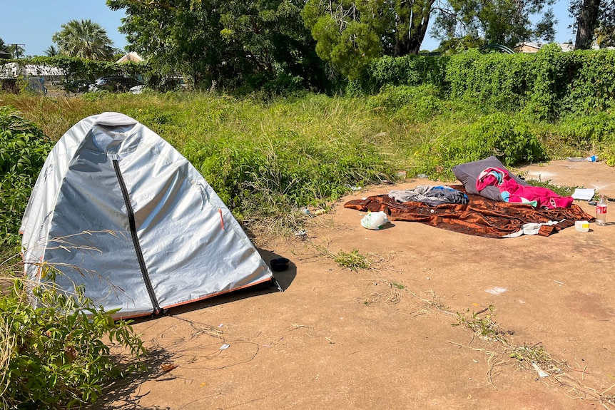 A tent next to some bedding outside on concrete.