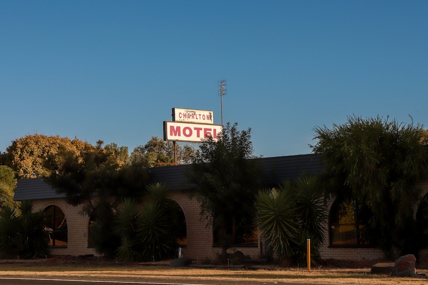 Exterior of an old 1970s brick motel at sunset with sun streaming onto building