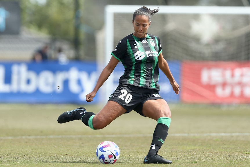 A Western United A-League Women player kicks the ball with her right foot.