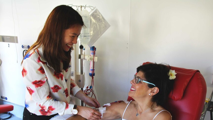 Nurse Ling Wei stands over dialysis patient Maree smiling at each other