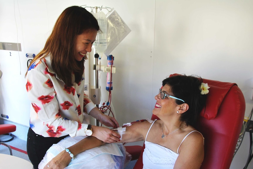 Nurse Ling Wei stands over dialysis patient Maree smiling at each other