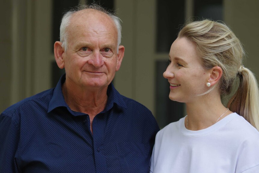 Older man and young woman looking at him, smiling