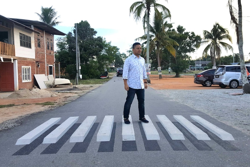 A Malaysian man stands on a three-dimensional zebra crossing optical illusion in Terengganu