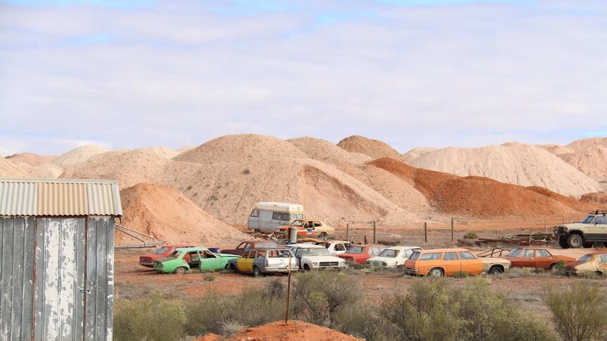 An outback town with hills and cars in the view.