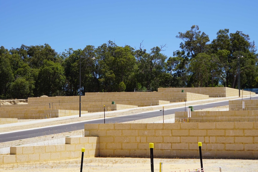 A wide shot of empty housing lots fronted by limestone block retaining walls at Paramount Estate in Baldivis.