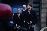 Two schoolgirls and their dad walk up the driveway