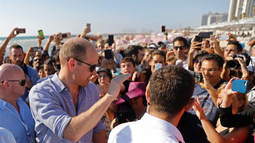 Prince William waves to crowds at a beach in Tel Aviv.