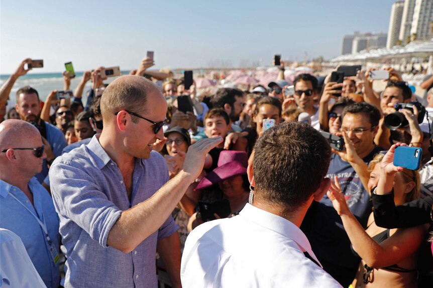 Prince William waves to crowds at a beach in Tel Aviv.