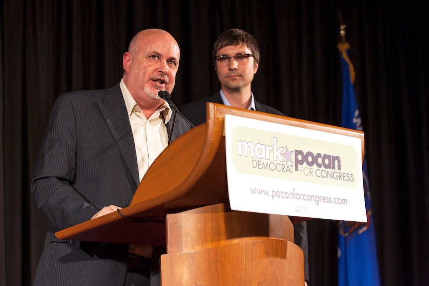 Mark Pocan stands at a podium with his husband, Philip Frank.