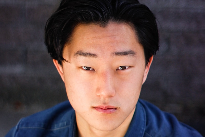 A man in a blue shirt with black hair looking up