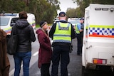 A woman talks to a police officer in the middle of a road
