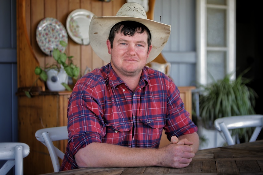 A man wearing a checked shirt and a large-brimmed hat.