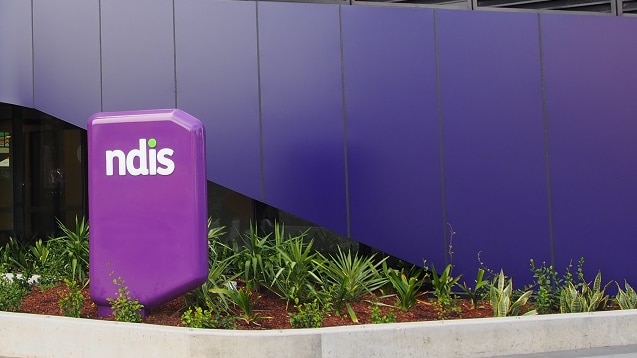 A glass office building with the purple NDIS sign out the front.