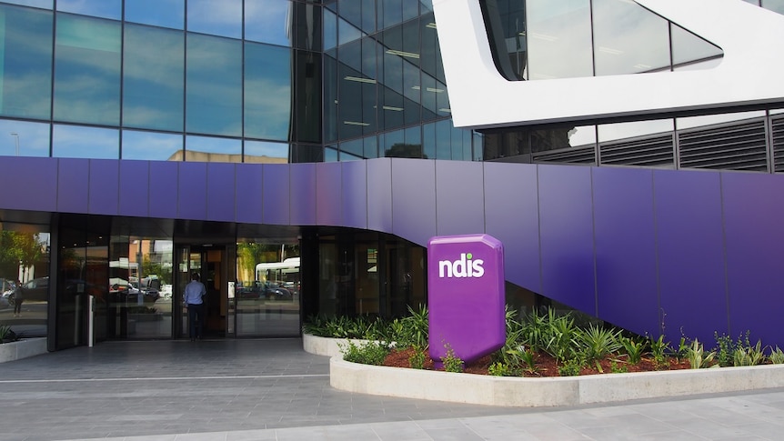 A glass office building with the purple NDIS sign out the front.