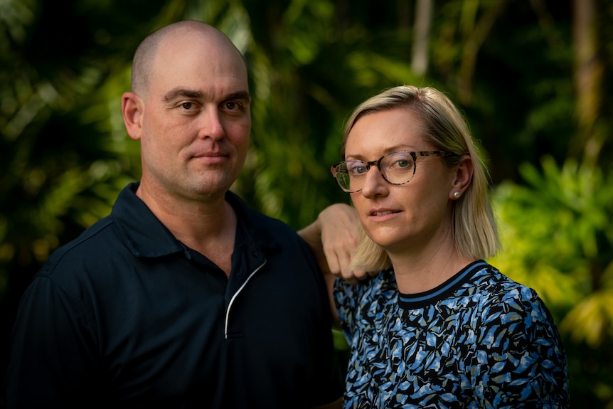 A Caucasian couple in their garden looking serious