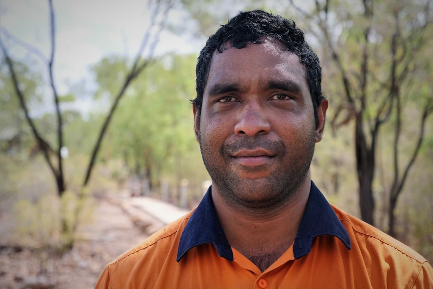 Close-up posed shot of man in workwear looking at camera in bush setting