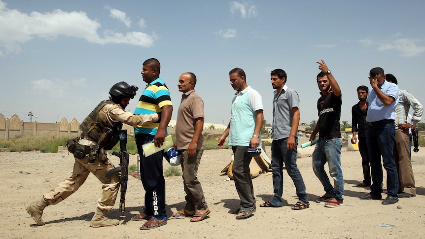 Iraqi civilian men are bodychecked as they volunteer to join fight against ISIS