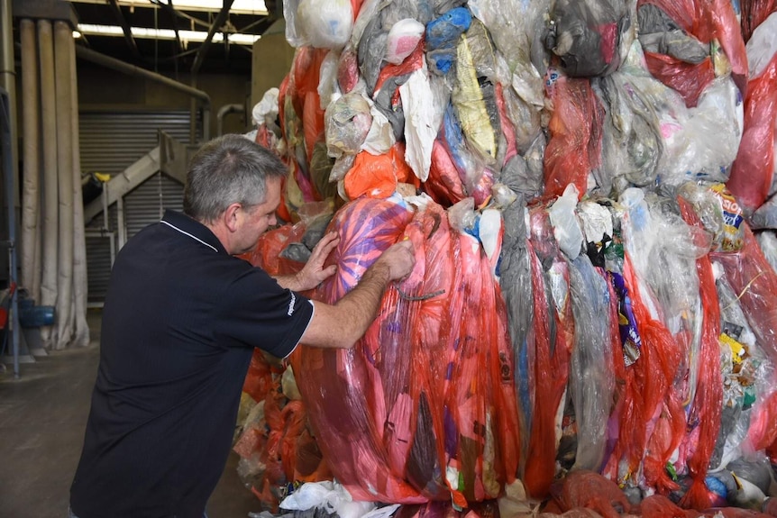 Mark Yates inspects some of the plastic bags of recycling.