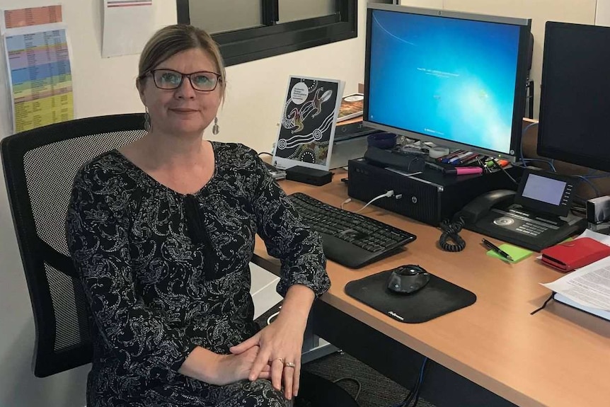 Woman sitting in office chair in front of desk and computer