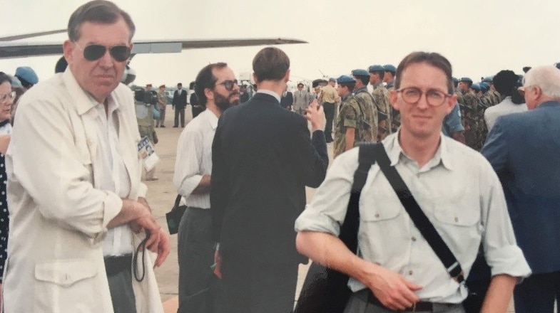 Harvey and Sunderland on tarmac at airport with soldiers and media behind them.