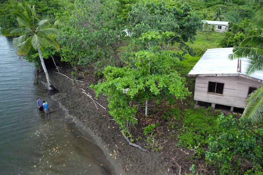 Men stand in the shallows near an abandoned village 