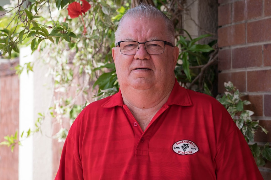 An older fellow in a red shirt squints at the camera.