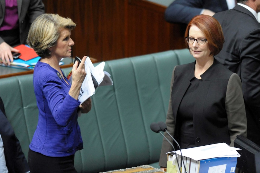 Julie Bishop and Julia Gillard pass during a division.