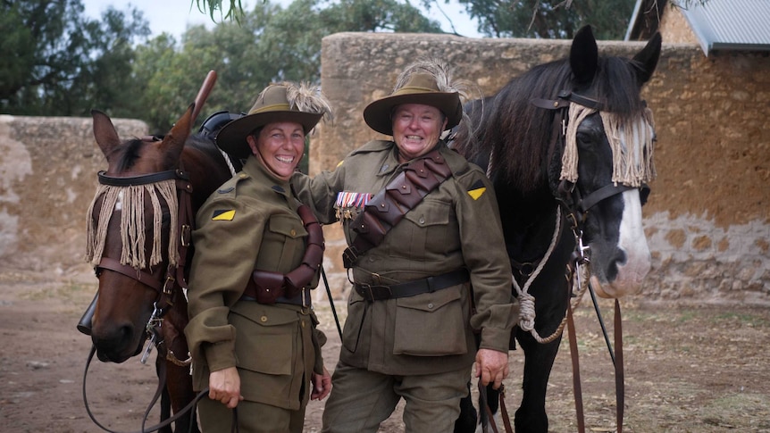 Natasha Pearce and Verna Holmes dressed in full World War I 10th Light Horse attire smiling, along with their horses.