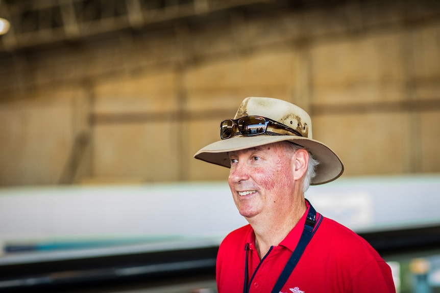 Older man in red t-shirt with hat on