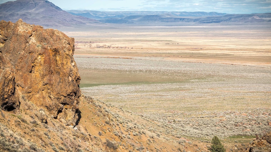 A mountain is seen in close proximity with the Alvord Desert spanning the horizon
