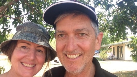 A man and woman smiling under a tree taking a selfie.