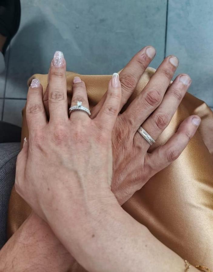 Hand of a man and a woman holding each other showing their wedding rings.