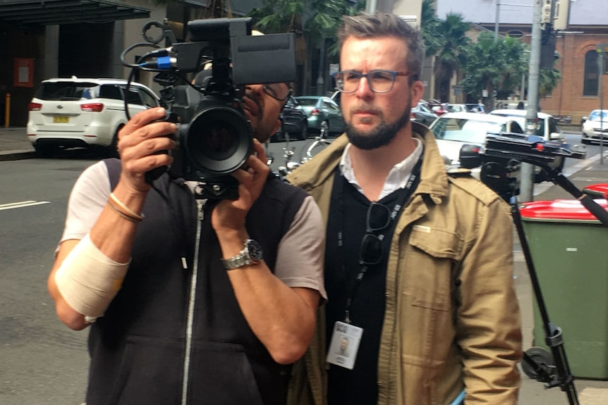 Cameraman and producer looking at camera viewfinder in city street.