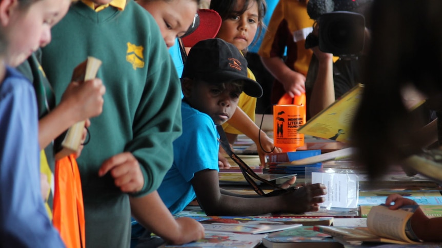 Kids look at a long table covered in books