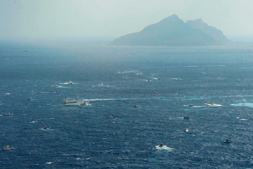 碧绿海水中的船只在雾中留下白线，双峰峰顶向远处。