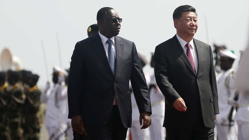 Xi Jinping walks with Macky Sall next to him with soldiers in the background
