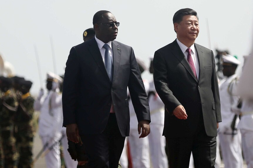 Xi Jinping walks with Macky Sall next to him with soldiers in the background