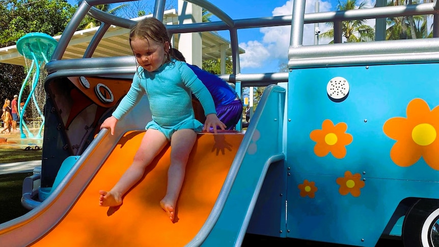 A little girl slides down a water slide.