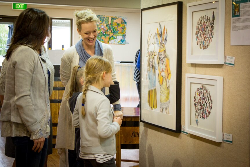 Penny Gill laughs as her two daughters study a painting of themselves.