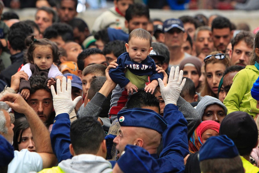 Migrant holds baby as policeman tries to maintain order Budapest, Hungary
