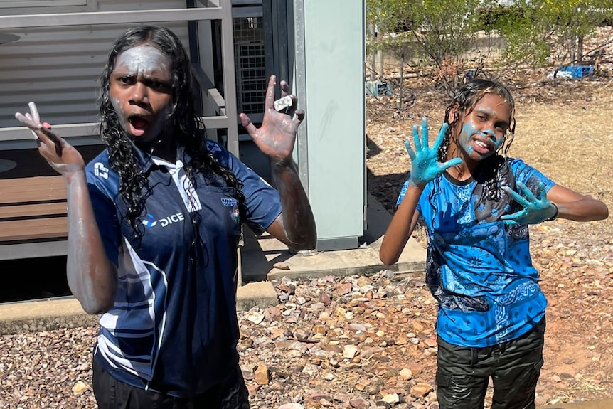 Two young Indigenous school girls, with paint on their hands, pose for a photo at the Howard Springs quarantine facility.