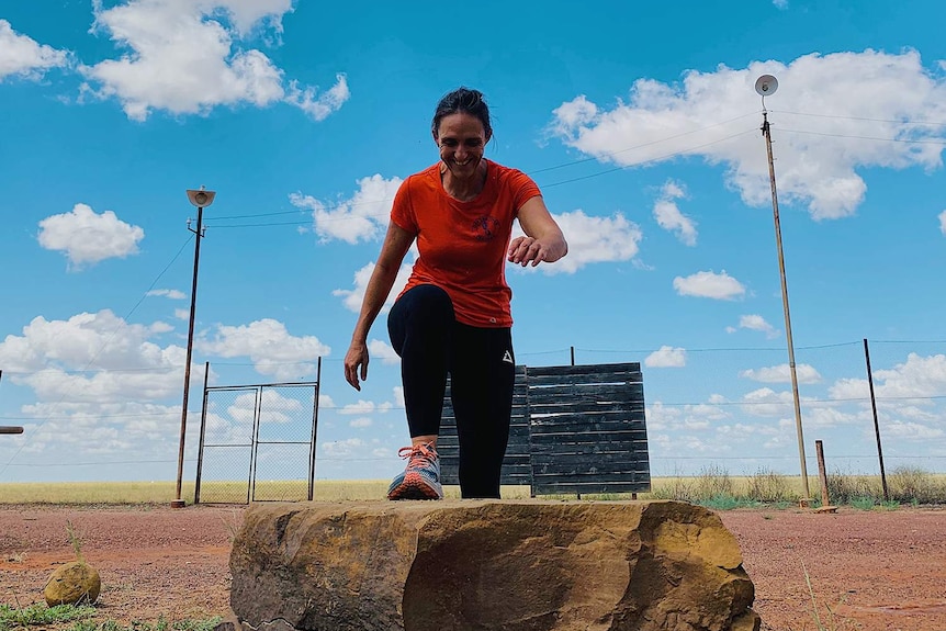 Joy McClymont working out in her yard under a blue cloudy sky.