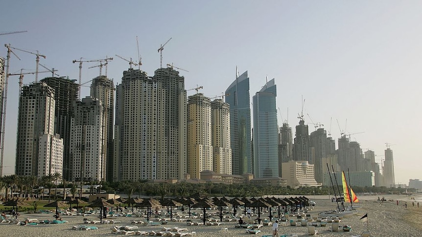 A beach is lined with a long row of high rises which are under construction